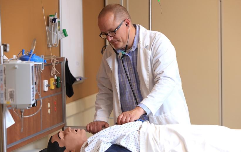 A nurse in a white coat practices in 澳门水利博彩官方网站's nursing simulation center.